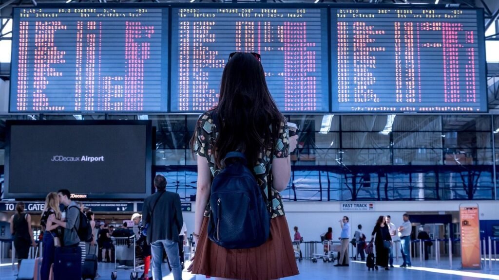 Traveler with backpack looking at airport flight departure board - Airport Travel Hacks Guide