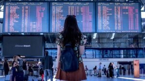 Traveler with backpack looking at airport flight departure board - Airport Travel Hacks Guide