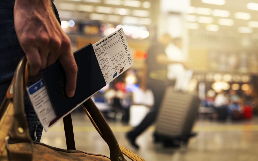 A traveler holding a passport and boarding pass at an airport, ready for departure.