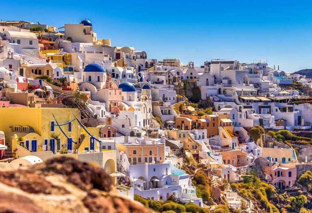 Scenic view of Santorini, Greece, featuring iconic white-washed houses with blue domes overlooking the Aegean Sea.